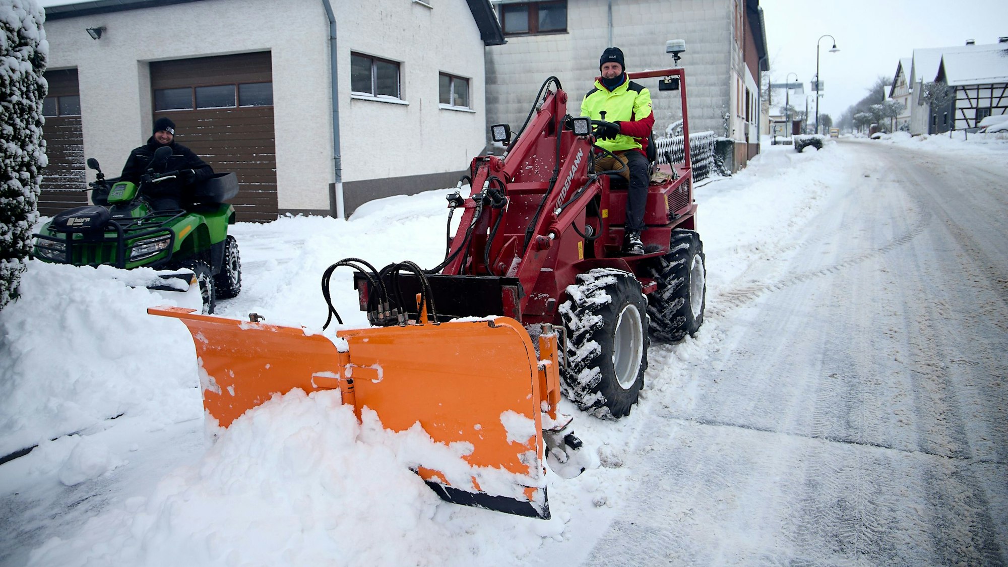 Mit einem Radlader räumt ein Mann Schnee von der Straße.