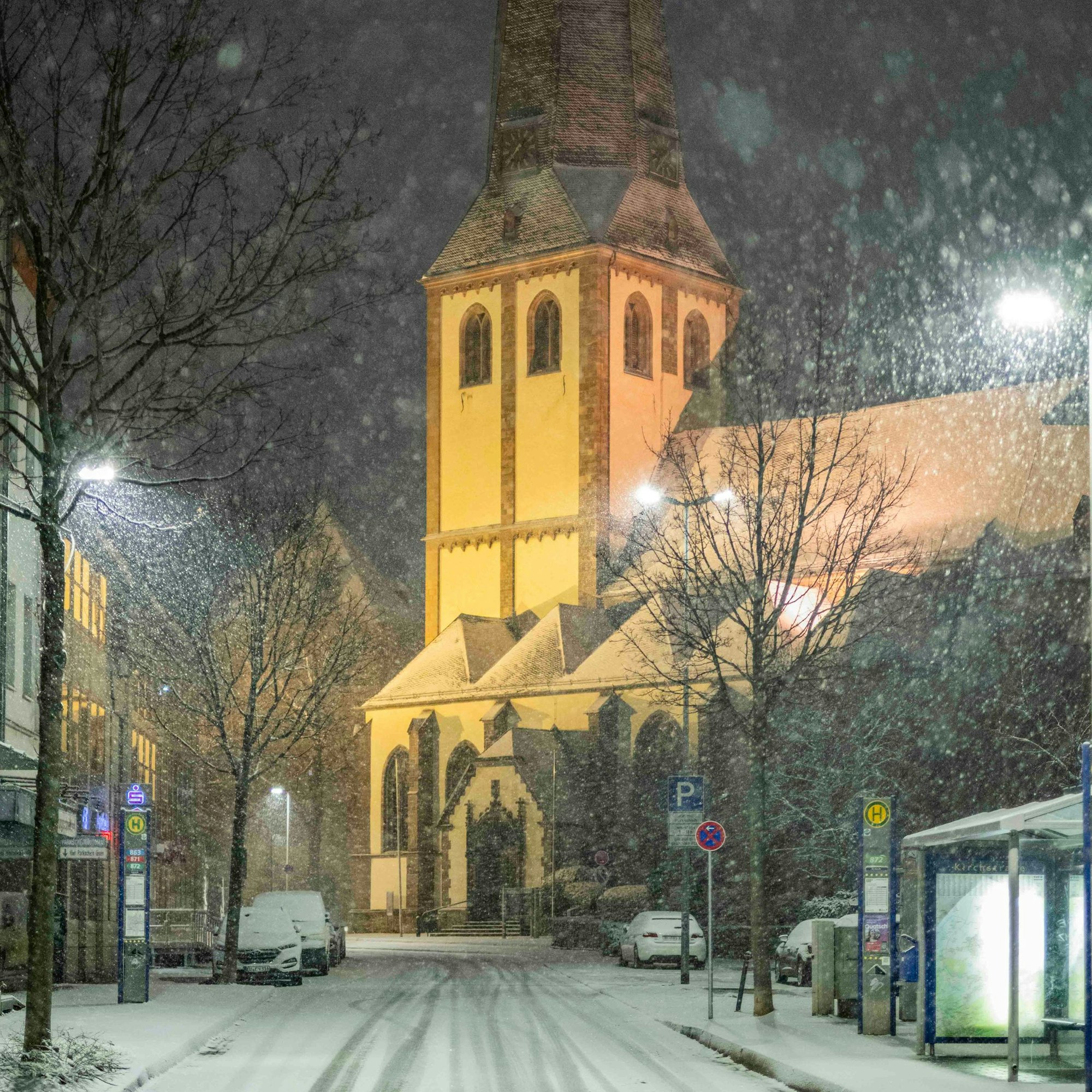Die Straße und die Bürgersteige vor der illuminierten Martinskirche in Euskirchen sind verschneit.