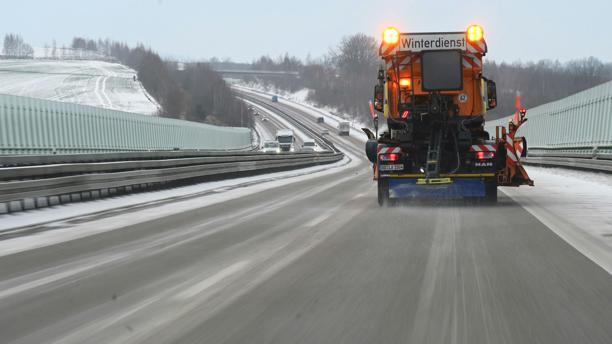 Ein Fahrzeug des Winterdienstes streut die Autobahn.