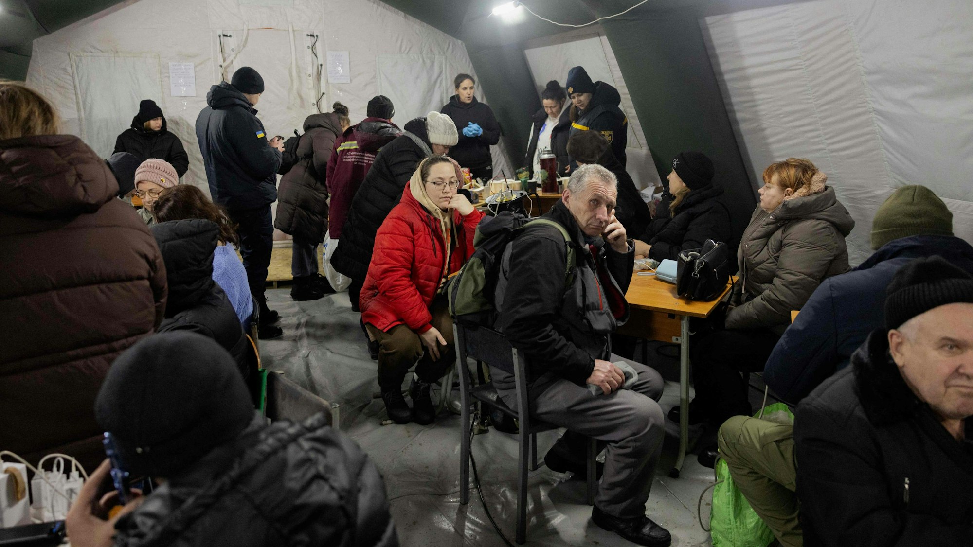 Menschen laden in einem Zelt eines „Punkts der Unbesiegbarkeit“ in Kiew ihre Geräte auf, nachdem russische Raketen- und Drohnenangriffe die ukrainische Energieinfrastruktur getroffen haben.