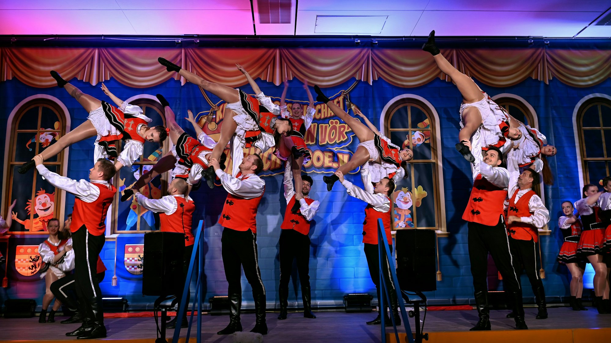 Die Aufnahme hält einen Moment auf der Bühne fest, bei dem Männer Frauen in der Luft über sich halten.