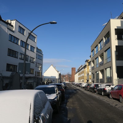 An einer Anwohnerstraße parken an beiden Fahrbahnrändern Autos.