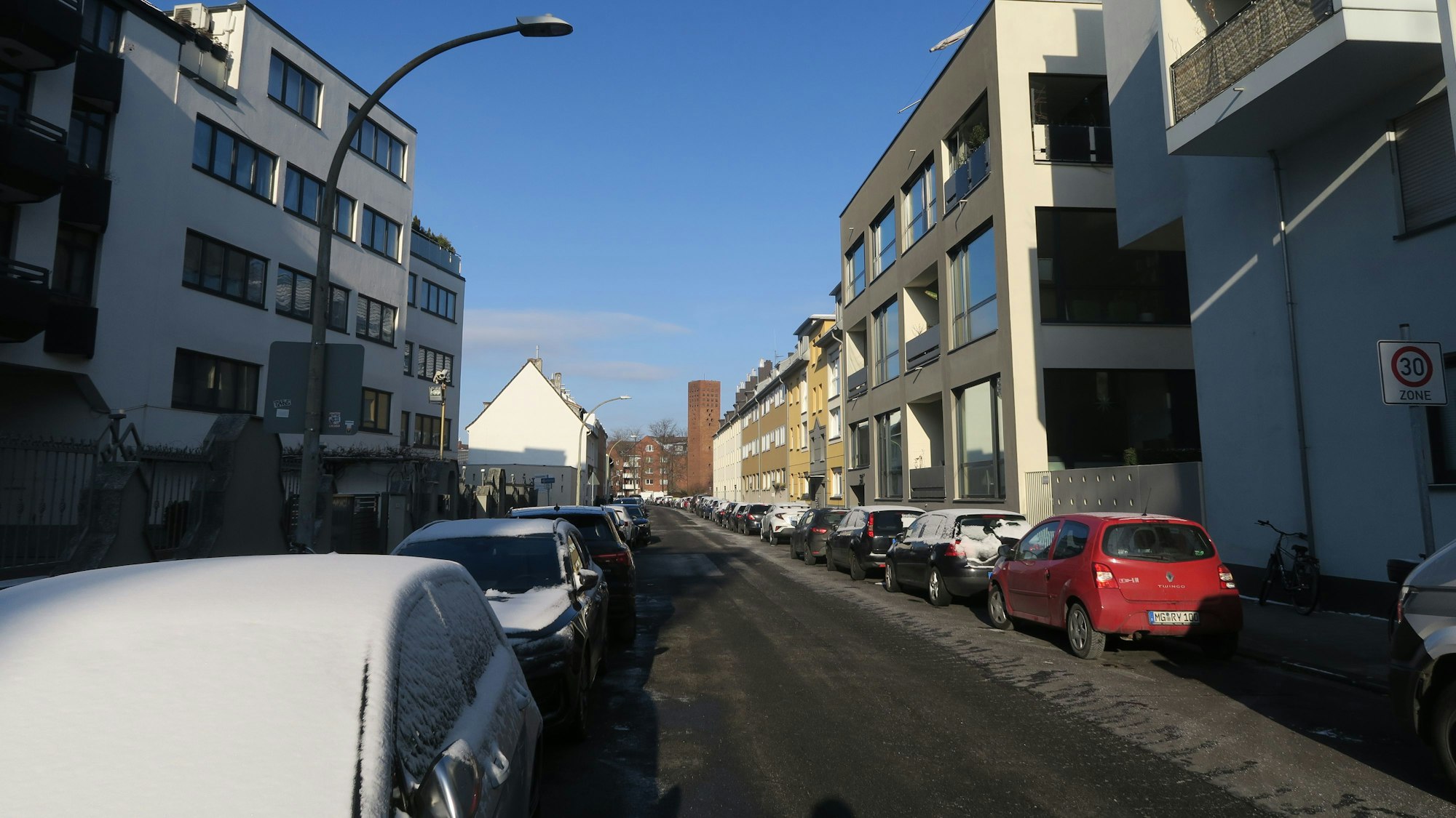 An einer Anwohnerstraße parken an beiden Fahrbahnrändern Autos.