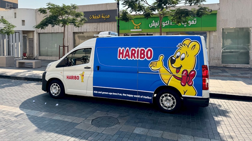 Ein Kleintransporter mit Goldbär und Haribo-Schriftzug ist in arabischer Straßenszene zu sehen.
