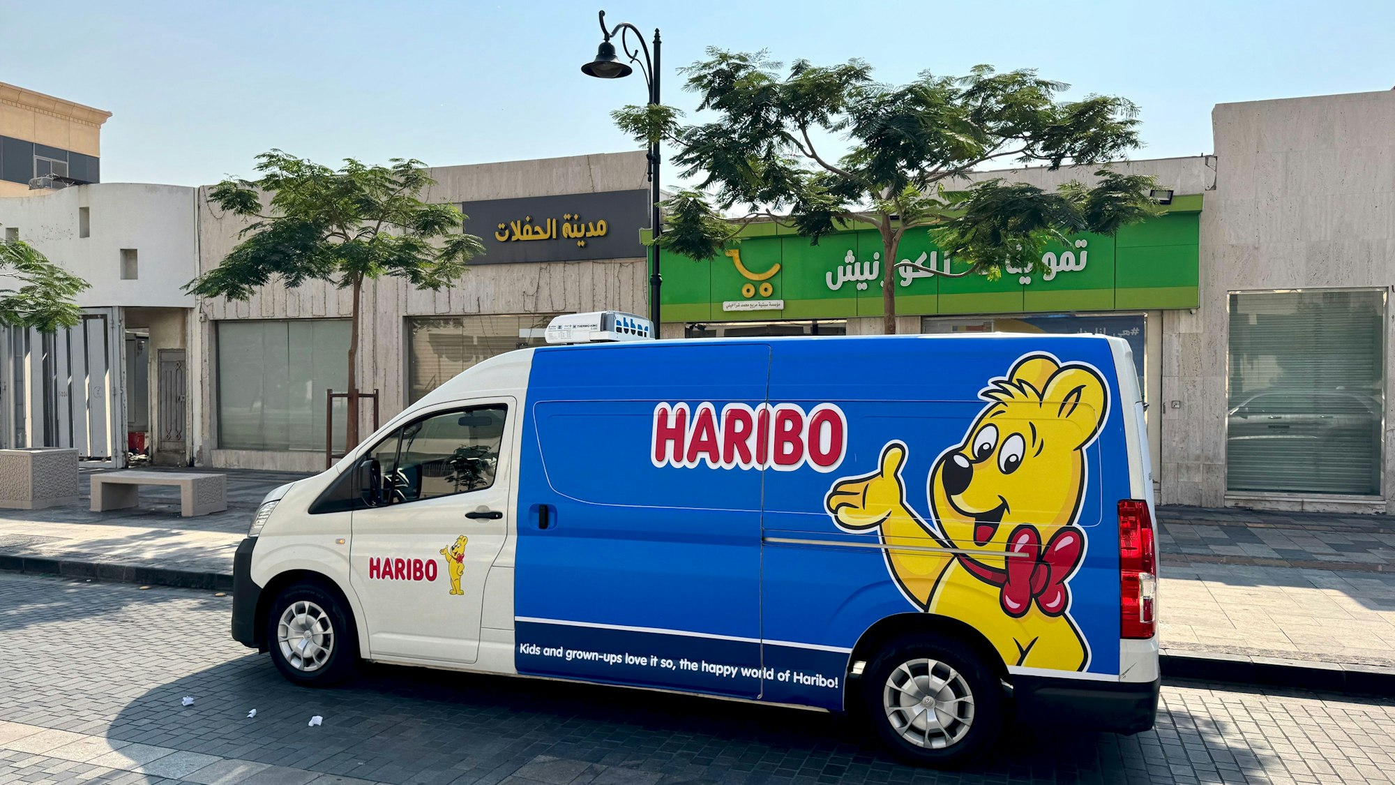 Ein Kleintransporter mit Goldbär und Haribo-Schriftzug ist in arabischer Straßenszene zu sehen.