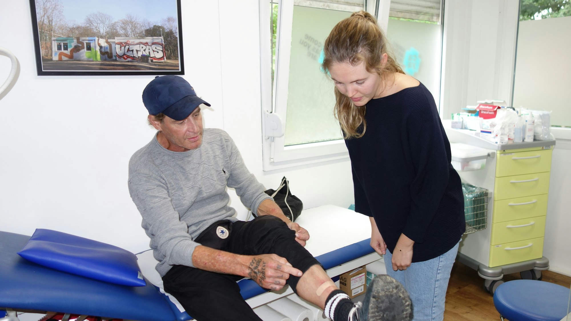 Eine Caya-Helferin schaut sich das Schienbein eines Patienten an.