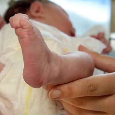 In einer Geburtsklinik an einem Krankenhaus hält eine Hebamme die Füßchen eines erst wenige Stunden alten Neugeborenes in ihren Händen. (Symbolbild)