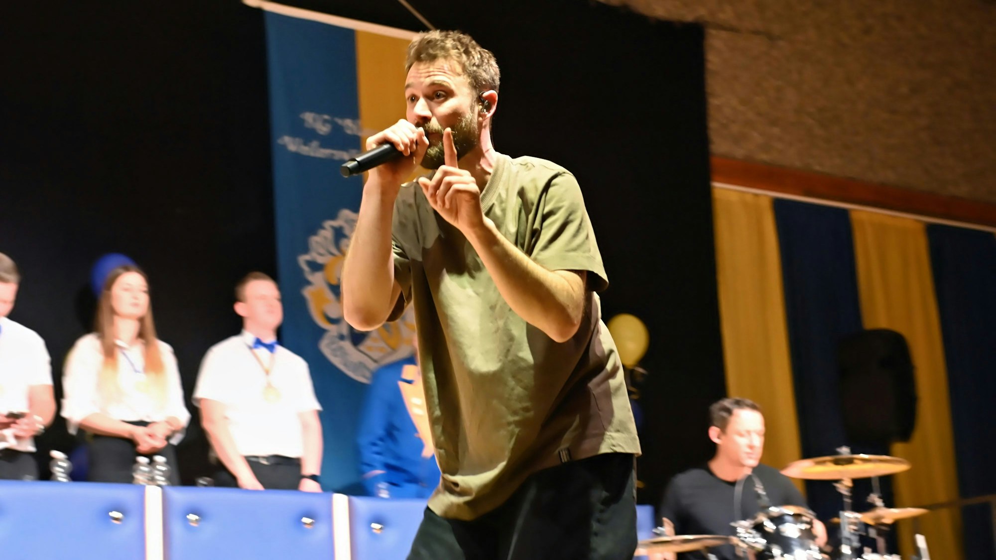 Der Sänger der Band „Stadtrand“ singt in ein Mikrofon.