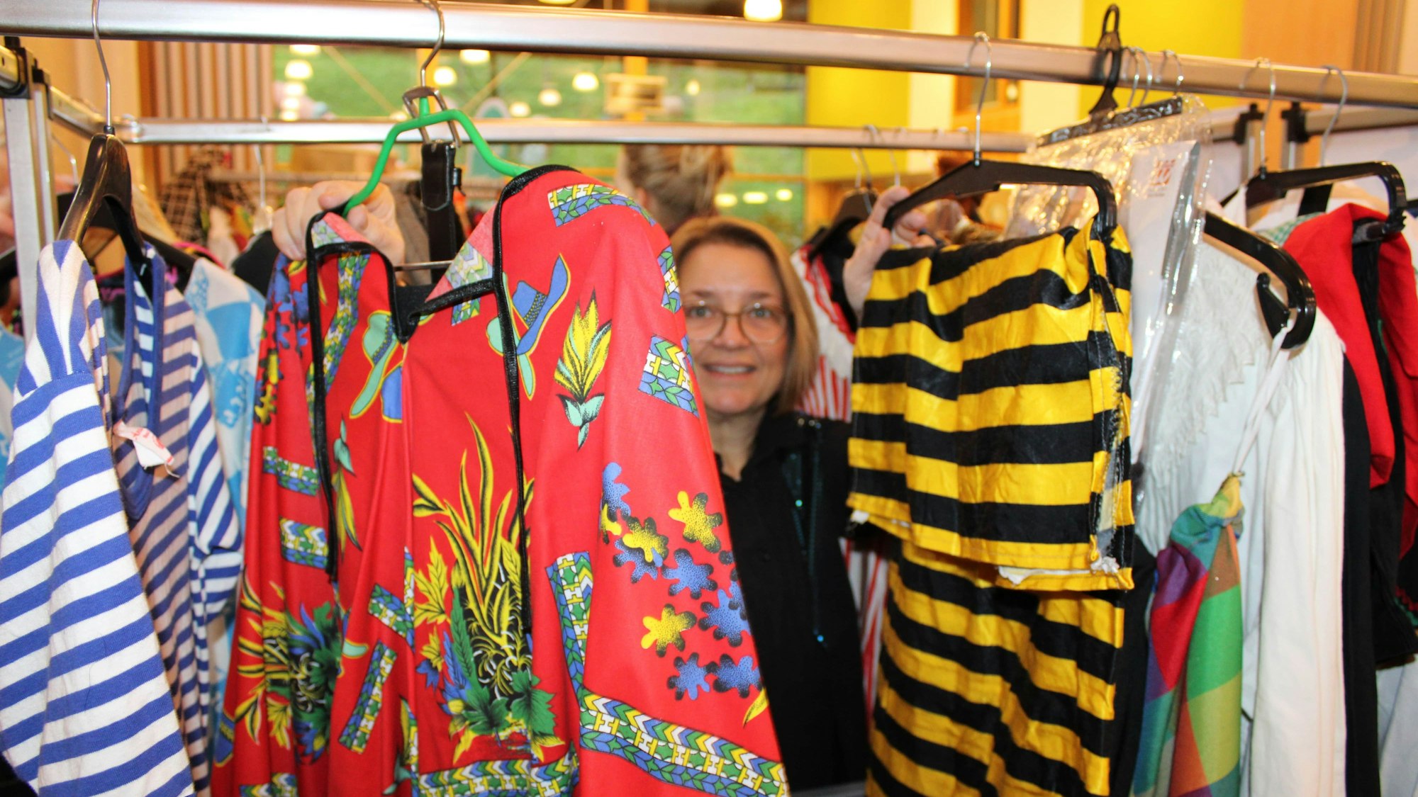 Eine Frau schaut durch auf einer Kleiderstange aufgereihte Kostüme.