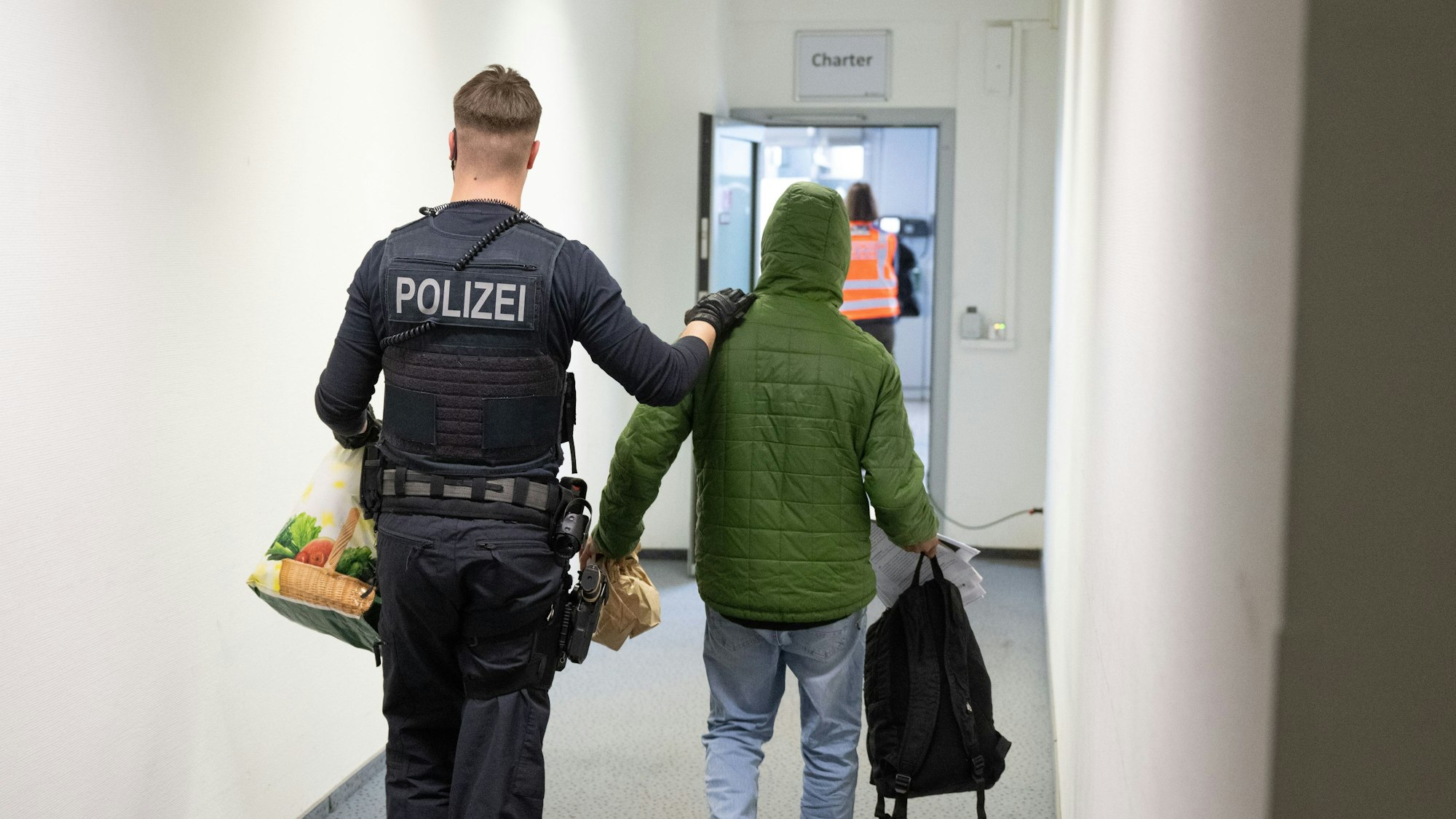 Ein Polizeibeamter bringt einen Mann zu einem Abschiebeflug.