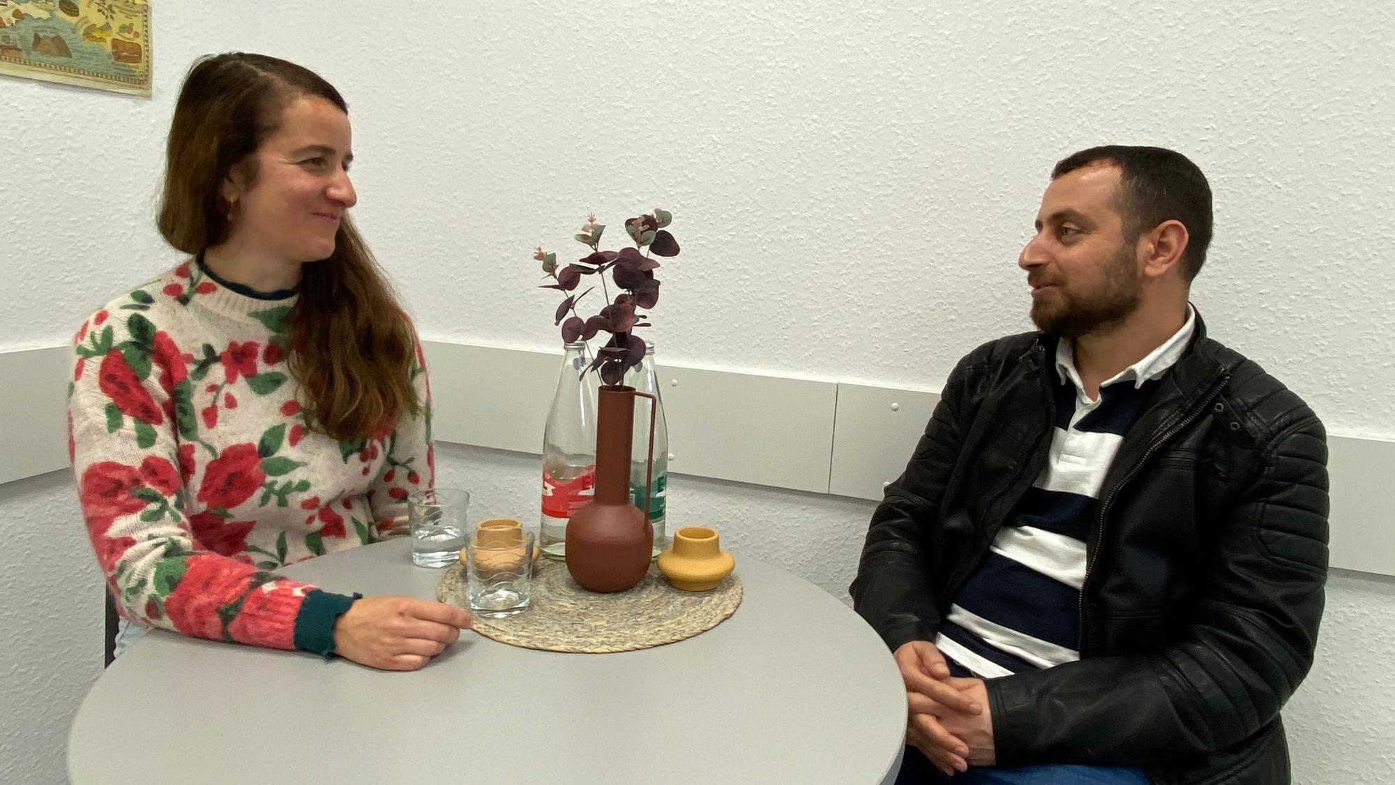 Die Kim-Case-Managerin sitzt im Gespräch mit ihrem Klienten an einem runden Tisch.