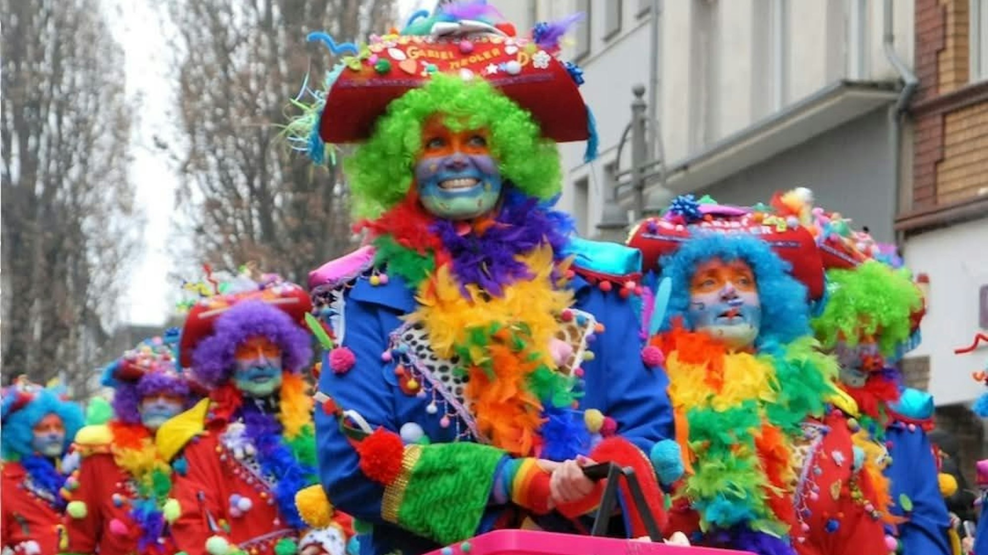 Zu sehen ist die farbenfroh kostümierte Gruppe im Karnevalszug.