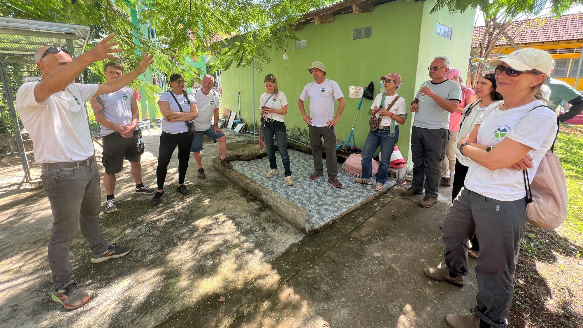 Die Mitglieder der Reisegruppe stehen vor dem grünen Gebäude eines Health Care Centers.