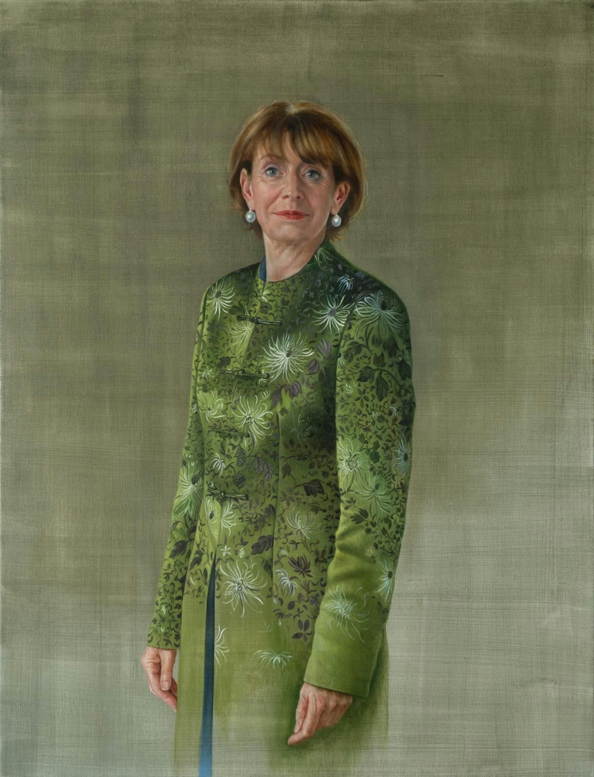 Henriette Reker steht im grünen Mantel vor einem grünen Hintergrund.