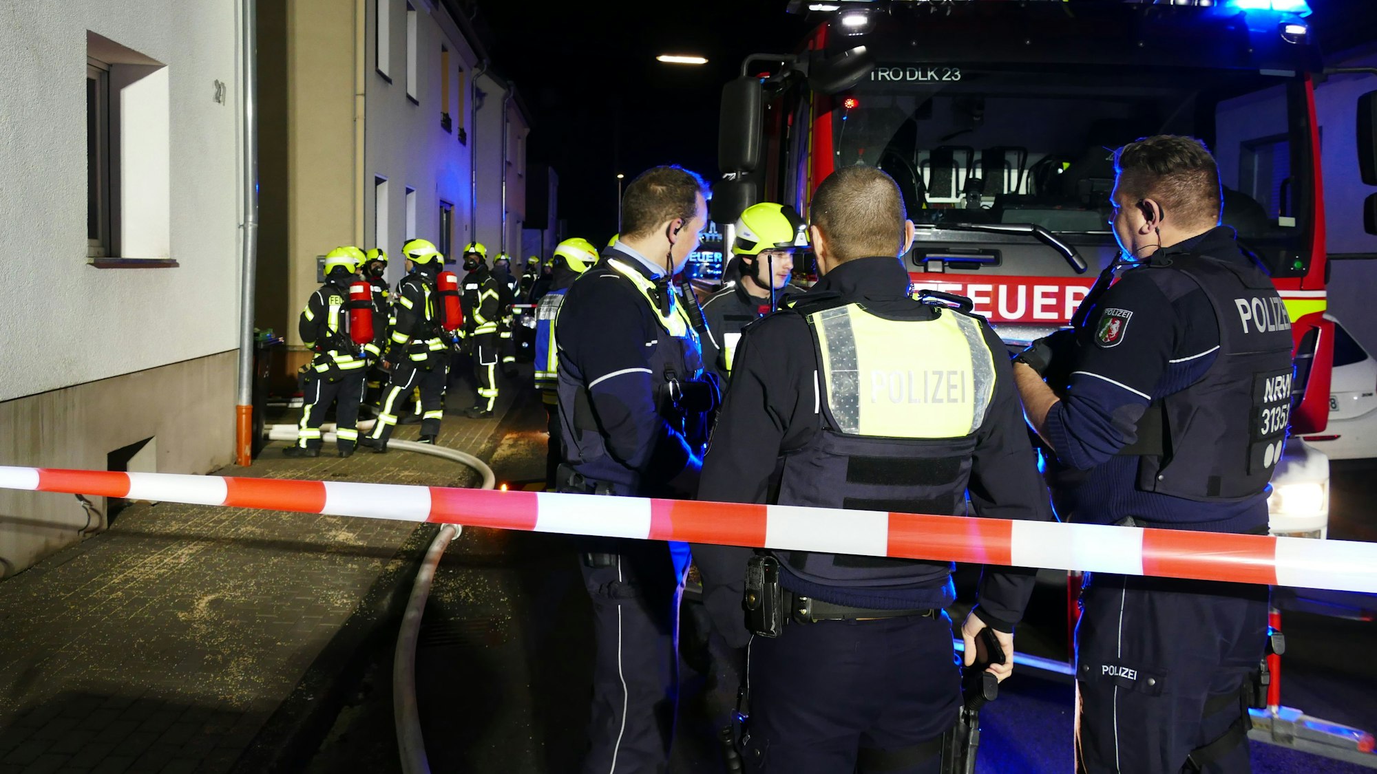 Ein Polizeiauto und ein Rettungswagen stehen nachts mit Blaulicht an einer Straße.