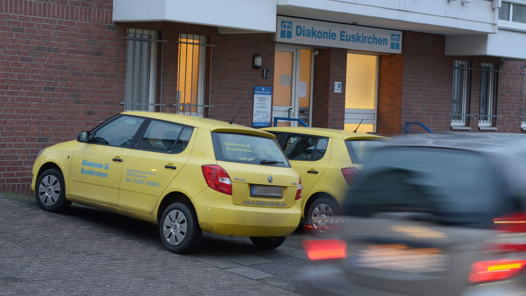Zwei Fahrzeuge des ambulanten Pflegedienstes stehen vor einem Gebäude der Diakonie.