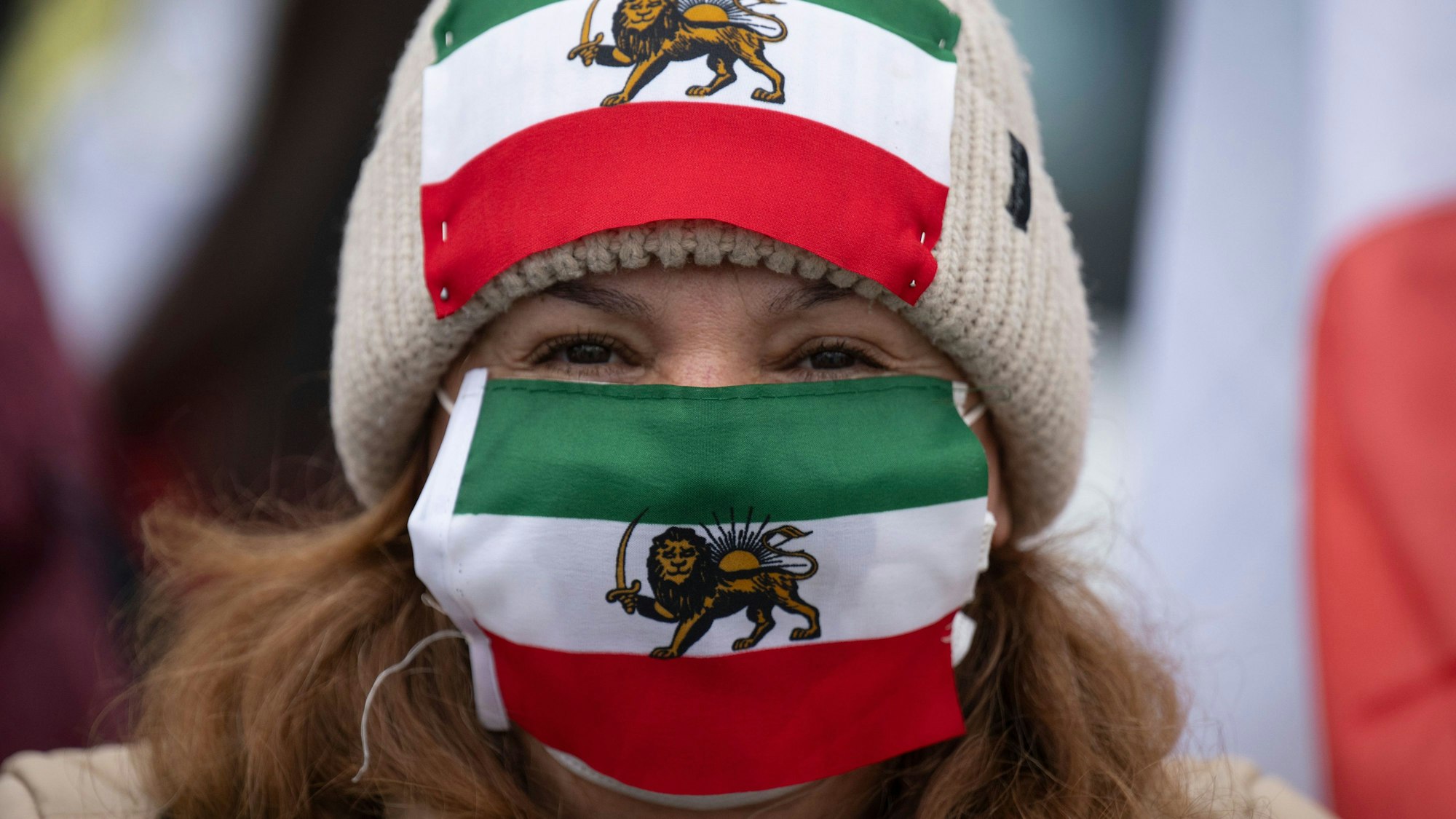 Auf einer Protestkundgebung in Frankfurt gegen das Regime in Iran zeigt eine Frau die alte iranische Flagge mit dem Löwen.