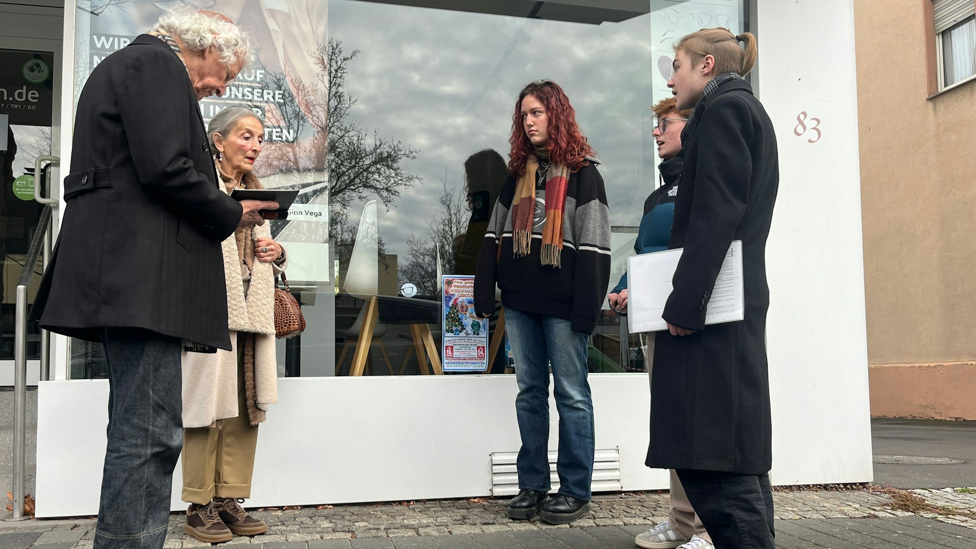 Roman Kovar (l.) liest mit Marie-Luise Jung und zwei Schülern und einer Schülerin den Kaddisch vor einem Stolperstein.