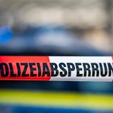 Ein Absperrband mit der Aufschrift «Polizeiabsperrung» ist vor einem Polizeiwagen aufgespannt.