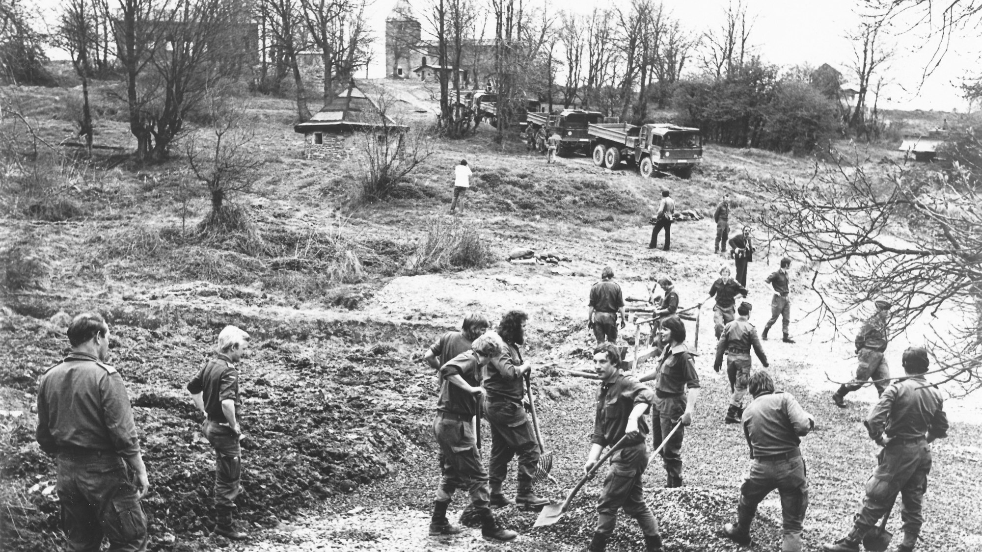 Das historische Schwarz-Weiß-Foto zeigt Soldaten, die eine Straße anlegen. Im Hintergrund ist die Kirchenruine von Wollseiffen zu erkennen.