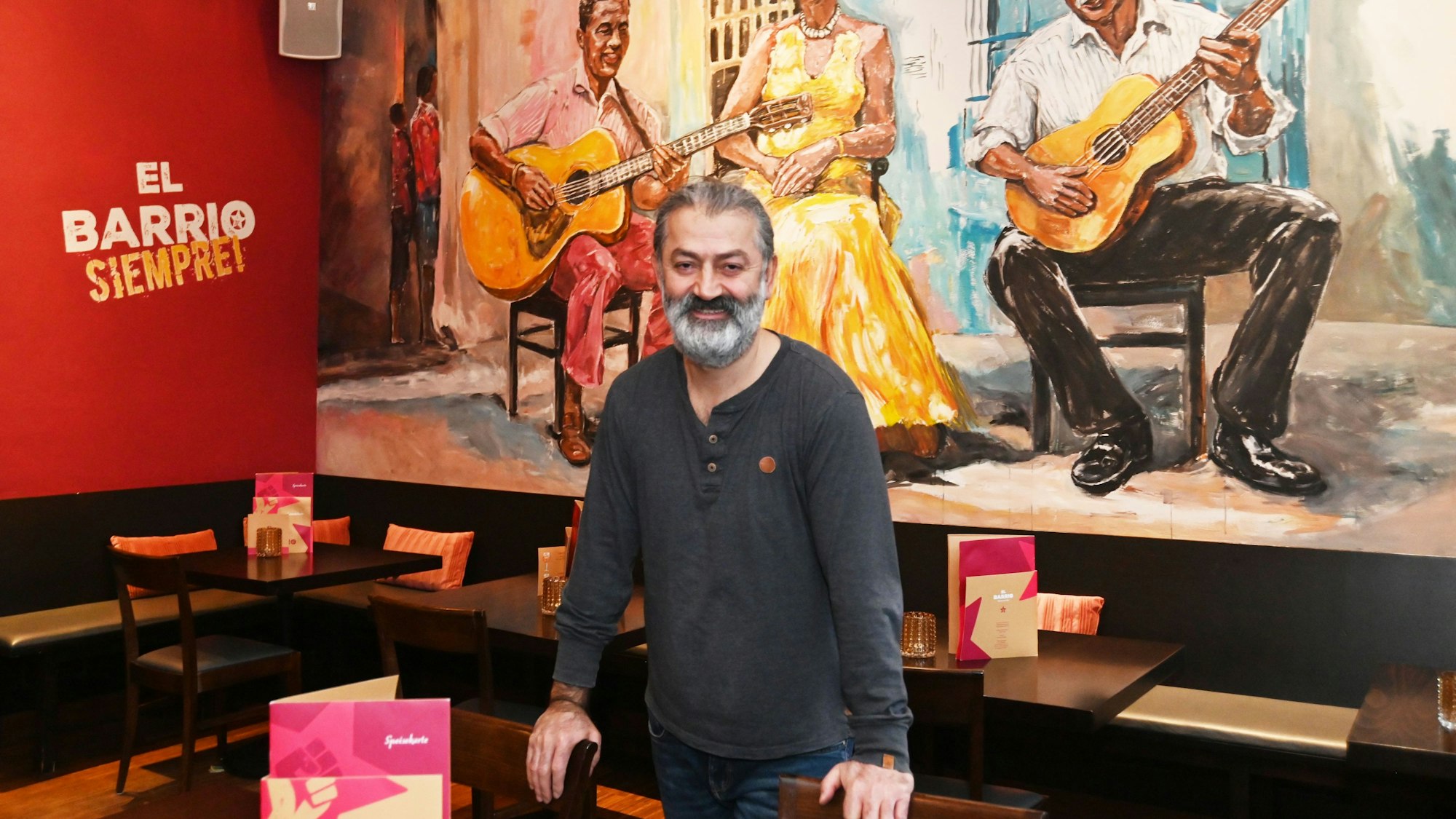 Barrio-Inhaber Ramazan Palanli ist vor einer bemalten Wand zu sehen.