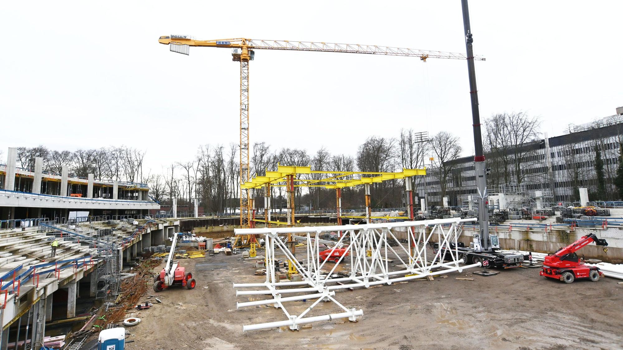 Im späteren Innenbereich der Radrennbahn wird gerade aus weißen Stahlrohren die Dachkonstruktion aufgebaut.