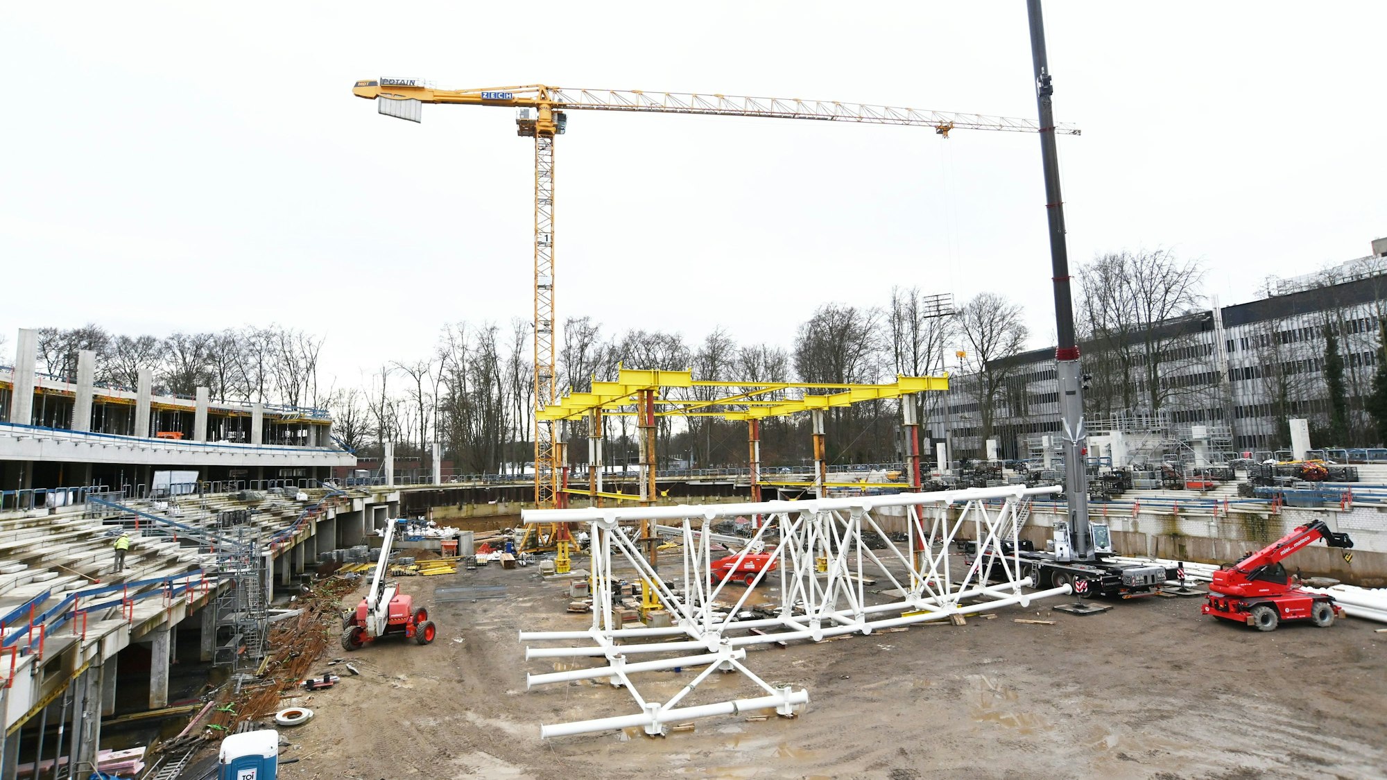 Im späteren Innenbereich der Radrennbahn wird gerade aus weißen Stahlrohren die Dachkonstruktion aufgebaut.