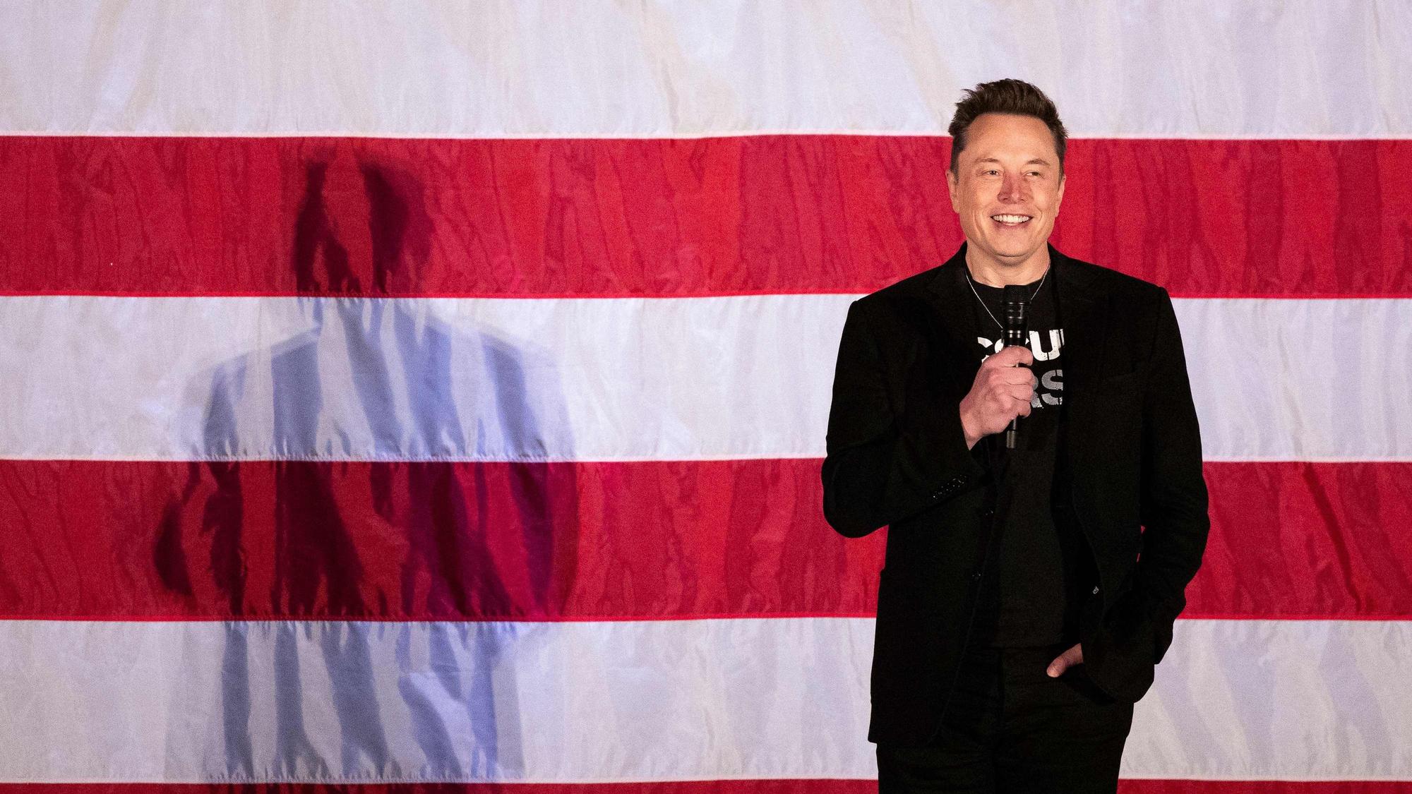 Elon Musk steht vor einer US-Flagge.