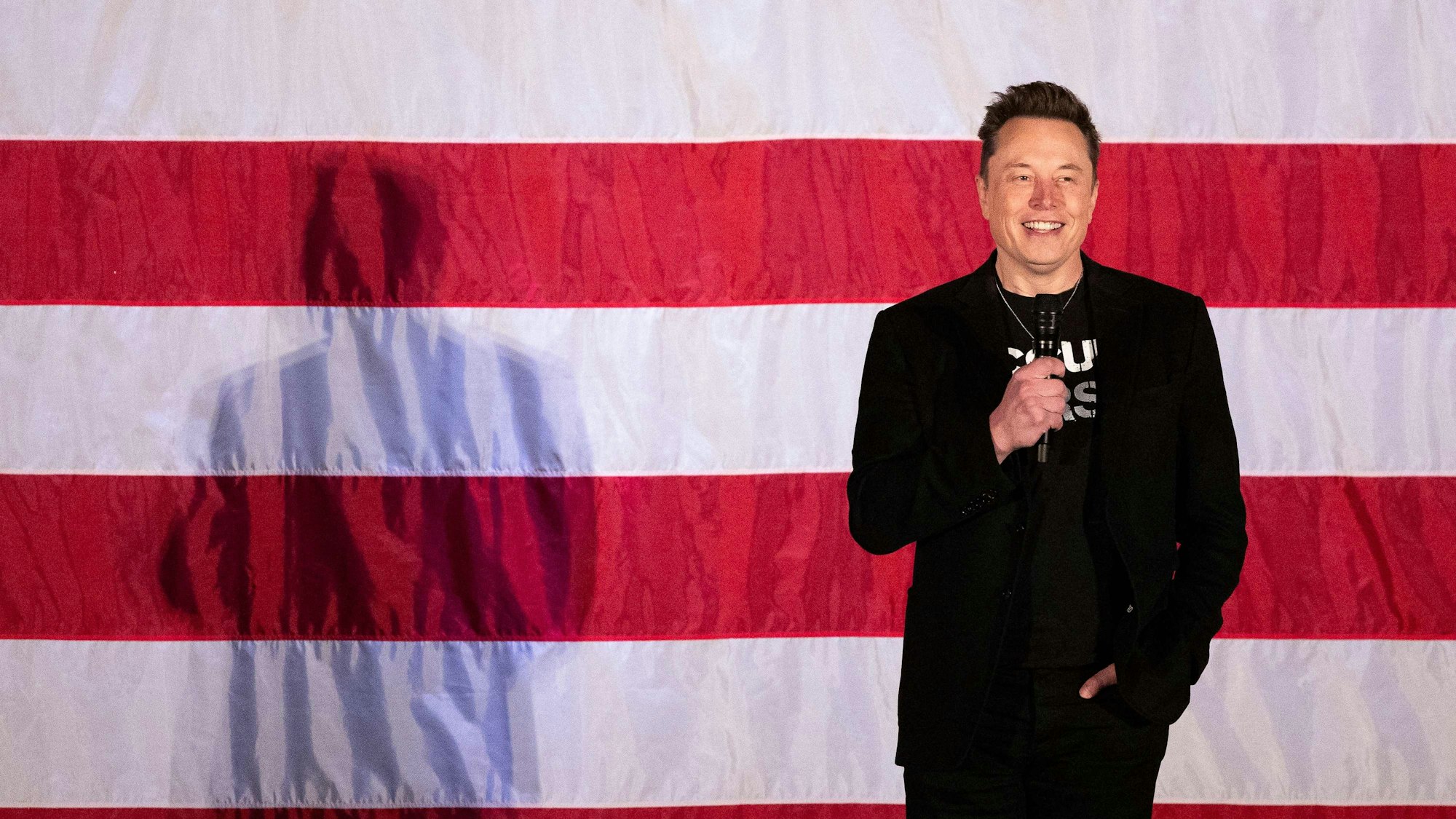 Elon Musk steht vor einer US-Flagge.