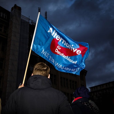 Ein Teilnehmer einer Demonstration der Partei AfD schwenkt eine Fahne