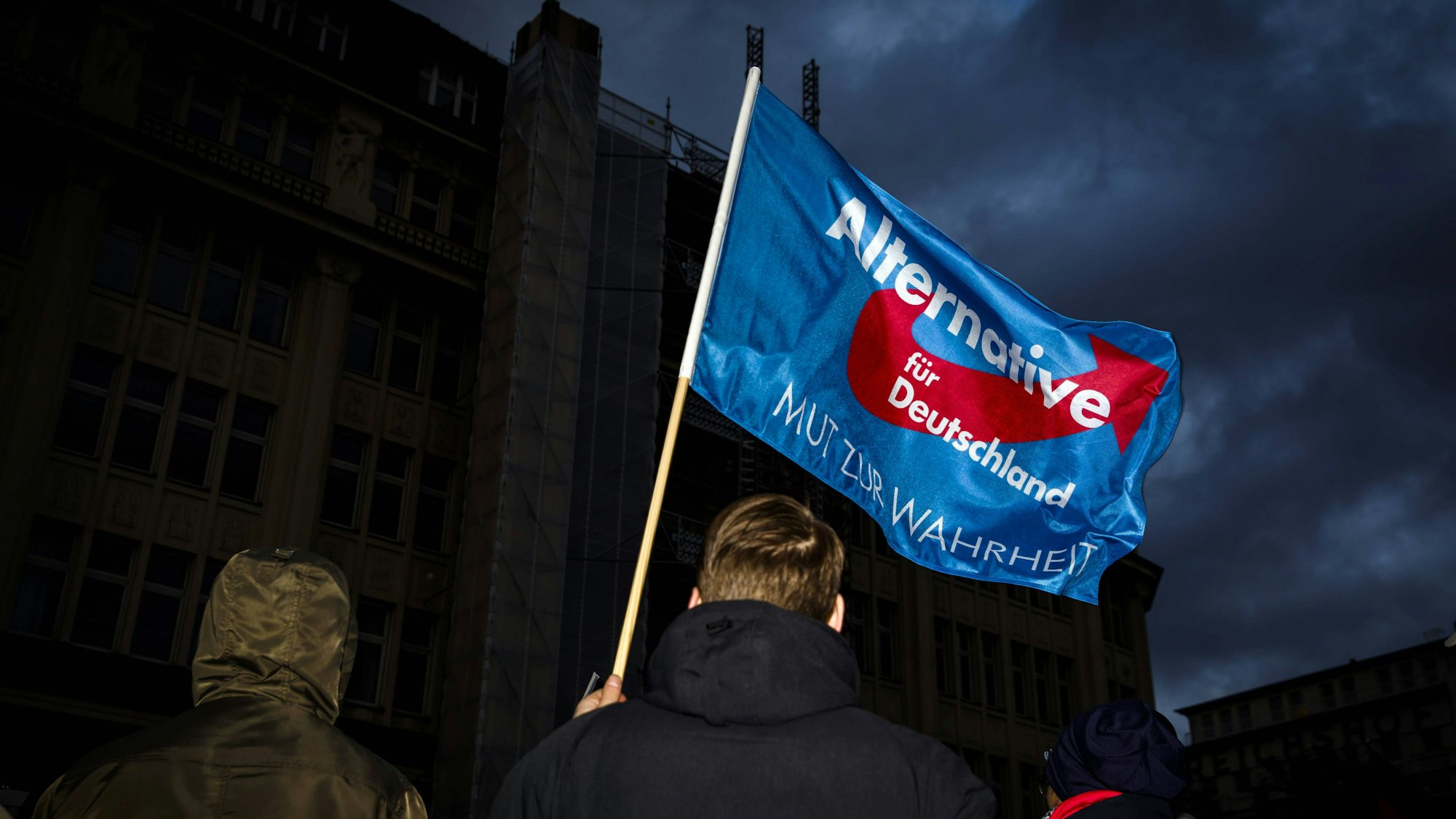 Ein Teilnehmer einer Demonstration der Partei AfD schwenkt eine Fahne