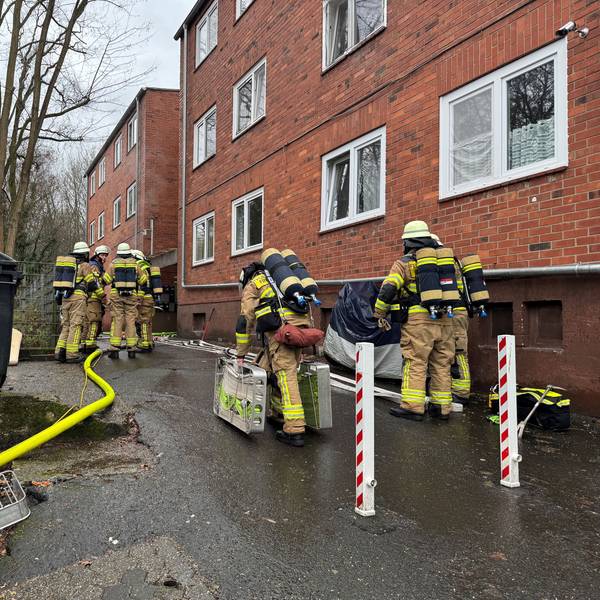 Auf dem Bild sind Feuerwehrleute vor einem Backsteingebäude zu sehen.