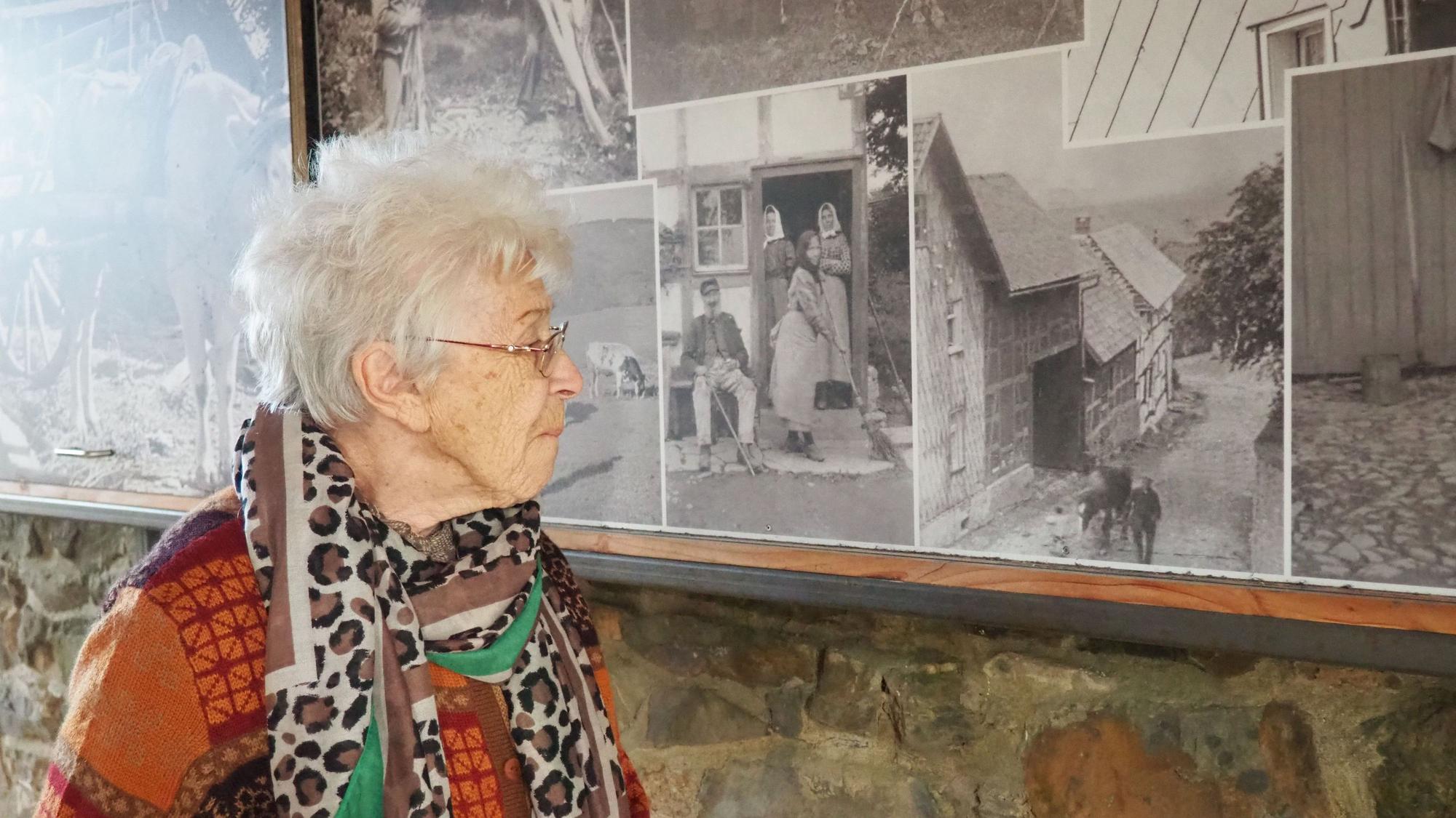 Christel Küpper steht vor einer Wand mit alten Fotos.