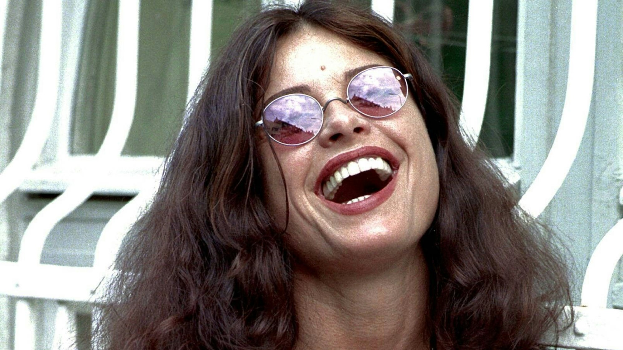 Uschi Obermaier lacht mit Sonnenbrille in die Kamera.