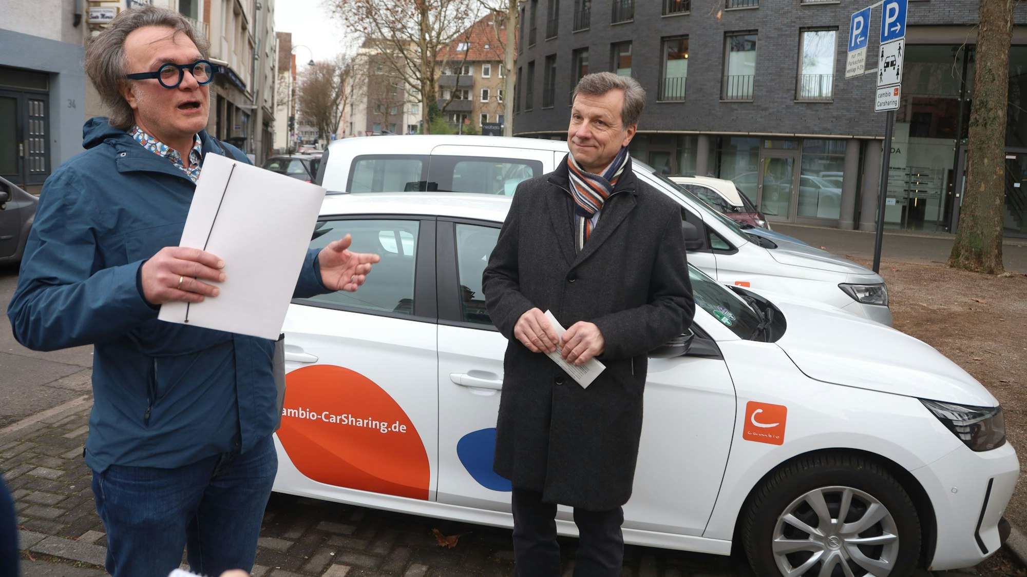 16.01.2026, Köln: Die Stadt Köln weiht die Carsharing-Station Salierring ein. An zahlreichen weiteren Standorten soll zukünftig auf öffentlichen Flächen das Parken geteilter Autos möglich sein. Zur Eröffnung einer der ersten Carsharing-Stationen im Rahmen dieses Ausbauvorhabens war auch Ascan Egerer (rechts), Beigeordneter für Mobilität der Stadt Köln dabei. Foto: Arton Krasniqi
