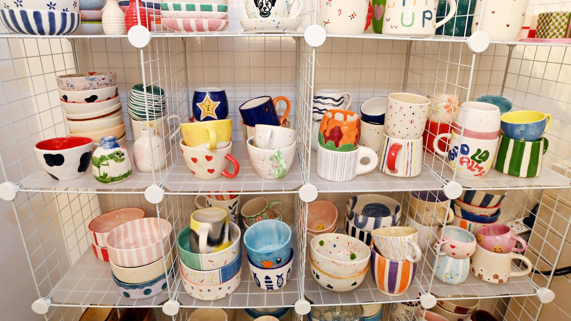 In einem regal stehen verschiedene bemalte Tassen und Schüsseln.