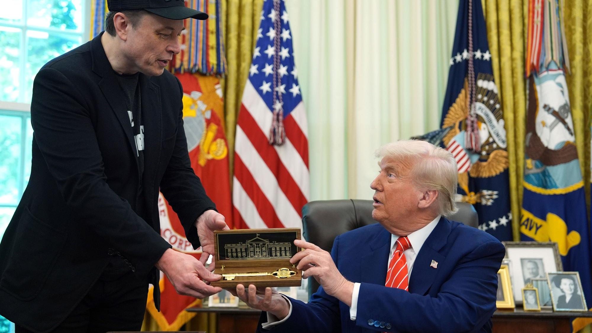 ARCHIV - 30.05.2025, USA, Washington: US-Präsident Donald Trump (r) überreicht seinem Berater Elon Musk einen Schlüssel während einer Pressekonferenz im Oval Office des Weißen Hauses. (zu dpa: ««Zu weit gegangen» – Musk bedauert Kritik an Trump») Foto: Evan Vucci/AP/dpa +++ dpa-Bildfunk +++