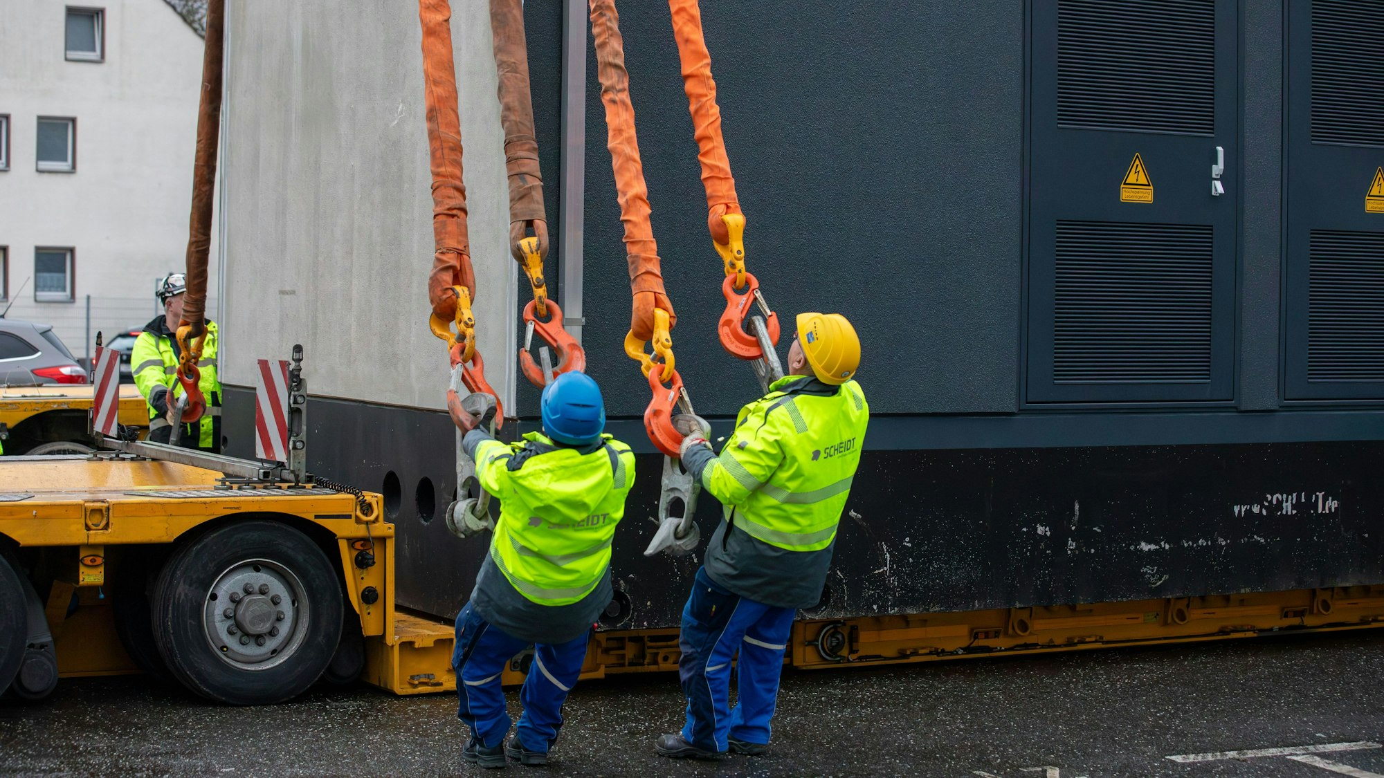 Mit einem Schwerlastkran werden Gebäudeteile für eine Trafostation in Porz transportiert.