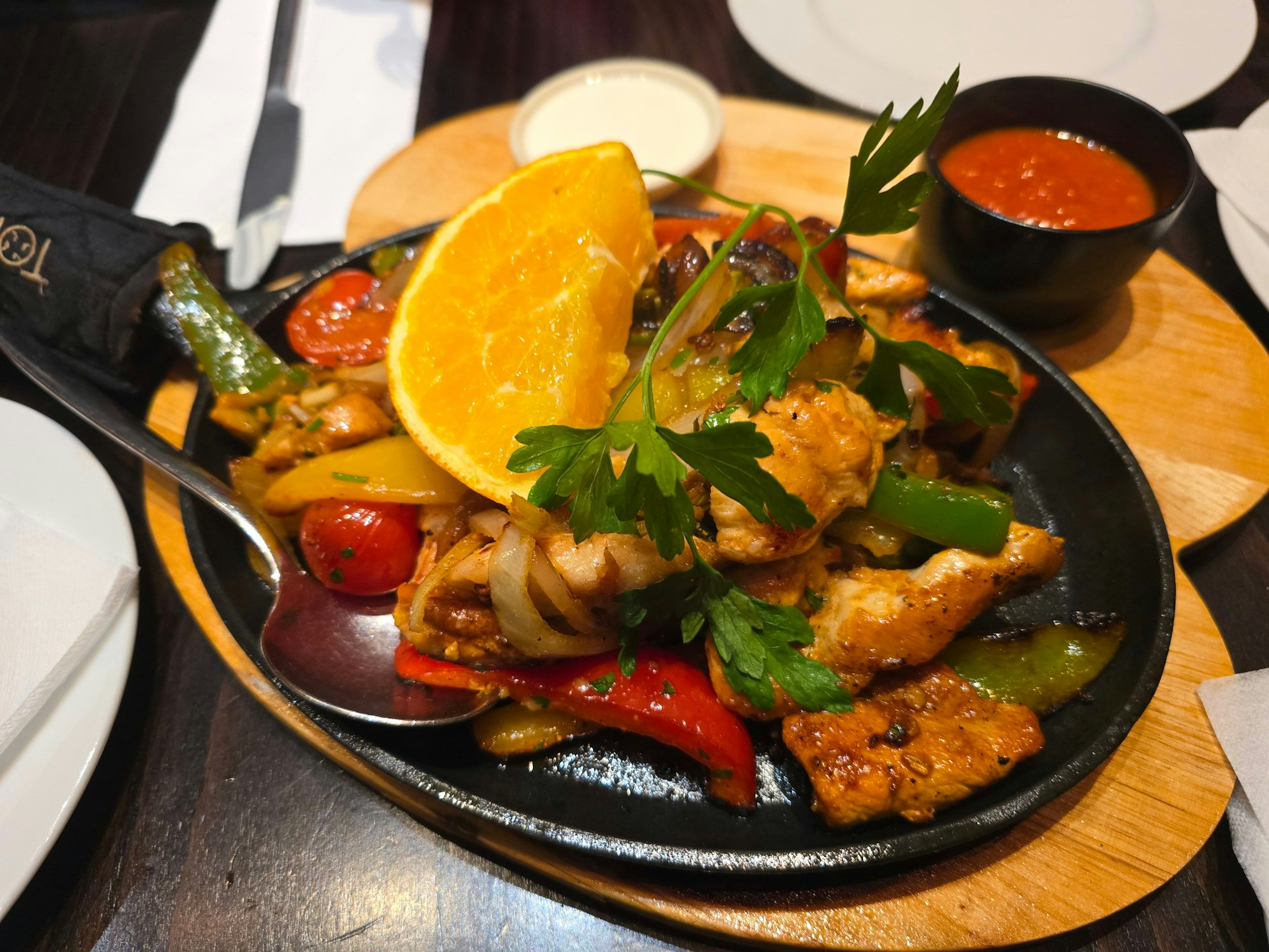 Eine Gusspfanne mit Hühnerfleisch, Paprika und Orange ist zu sehen.