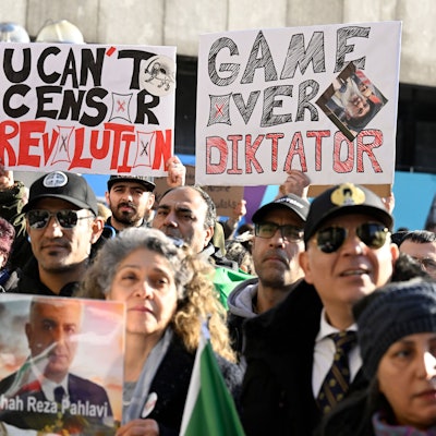 Teilnehmende halten bei einer Demonstration Schilder und Fahnen zur Unterstützung der Proteste im Iran.