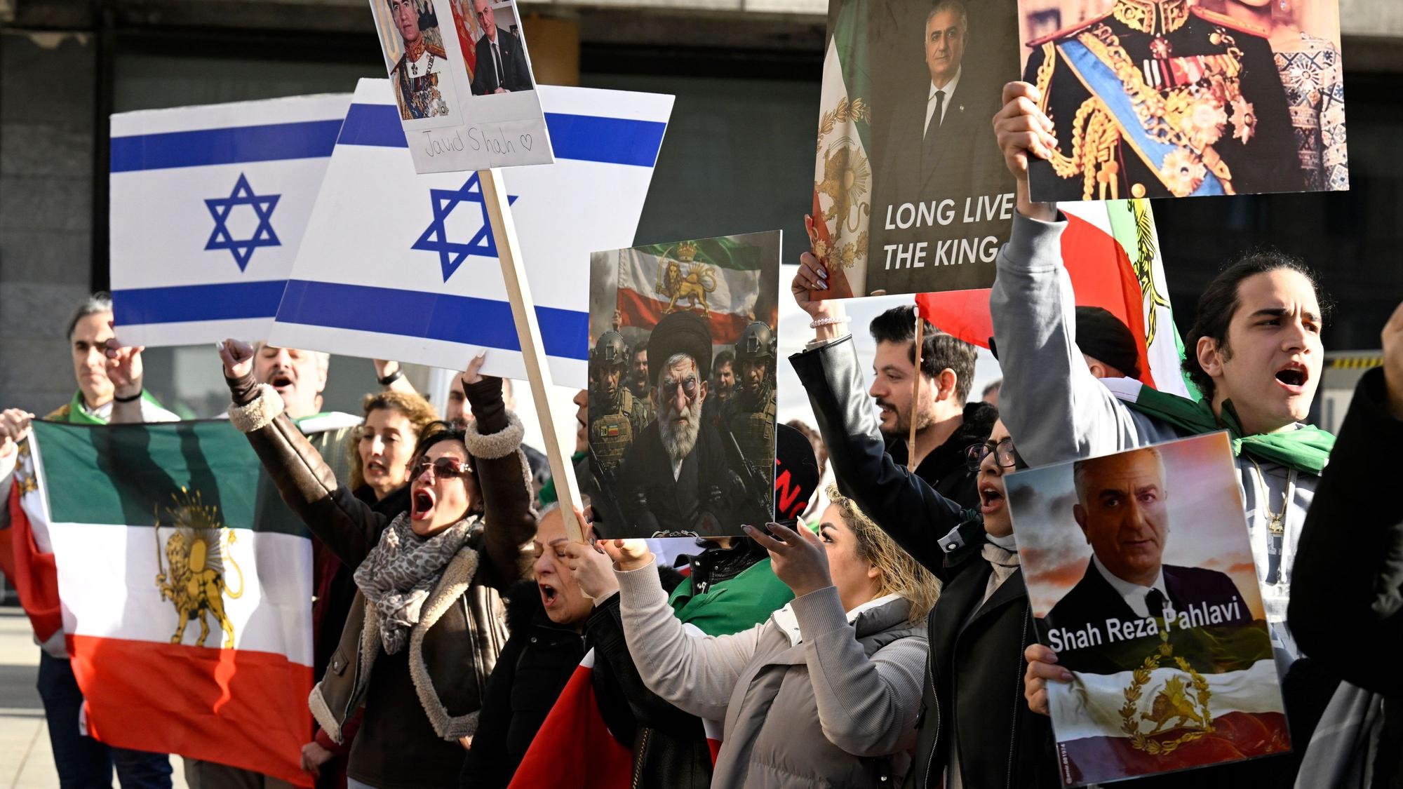 Teilnehmende halten bei einer Demonstration Schilder und Fahnen zur Unterstützung der Proteste im Iran.