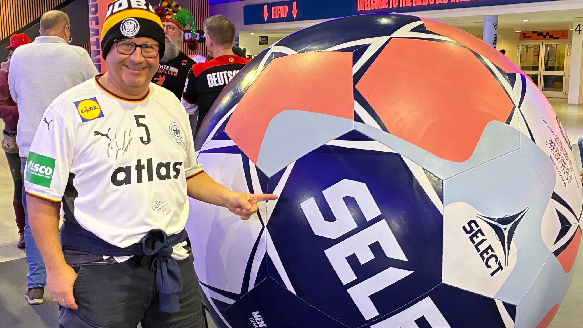Ein Mann steht vor einem überdimensionalen Handball.