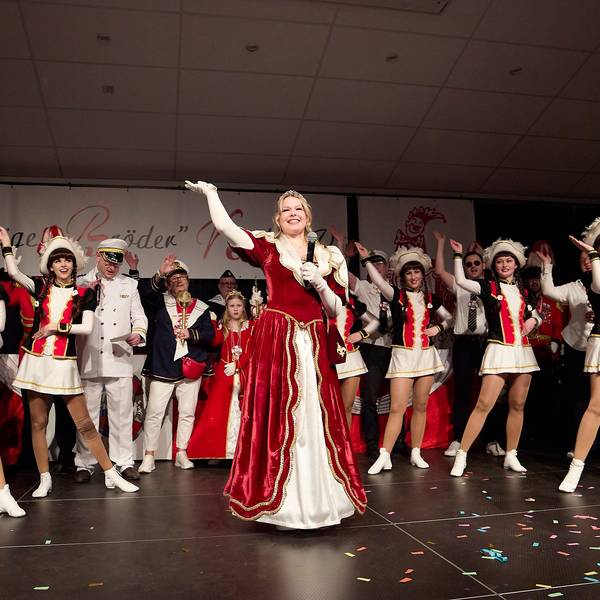 Prinzessin Emily I., die neue Tollität der Löstige Bröder Kall, winkt strahlend von der Bühne ins Publikum. Hinter ihr stehen die Tänzerinnen der Kallbachmücken in ihrem Ornat.