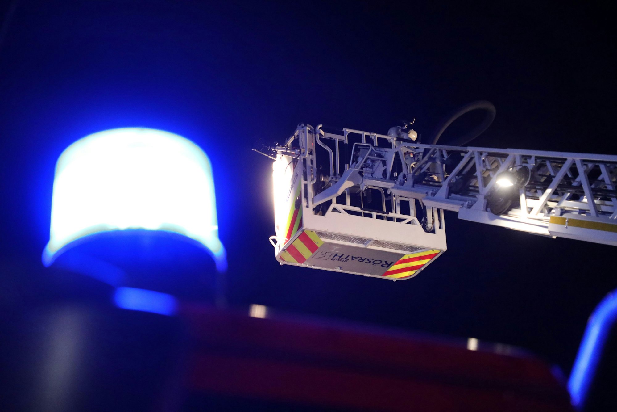 Neben einem Blaulicht ist der Korb der Drehleiter der Feuerwehr Rösrath zu sehen.