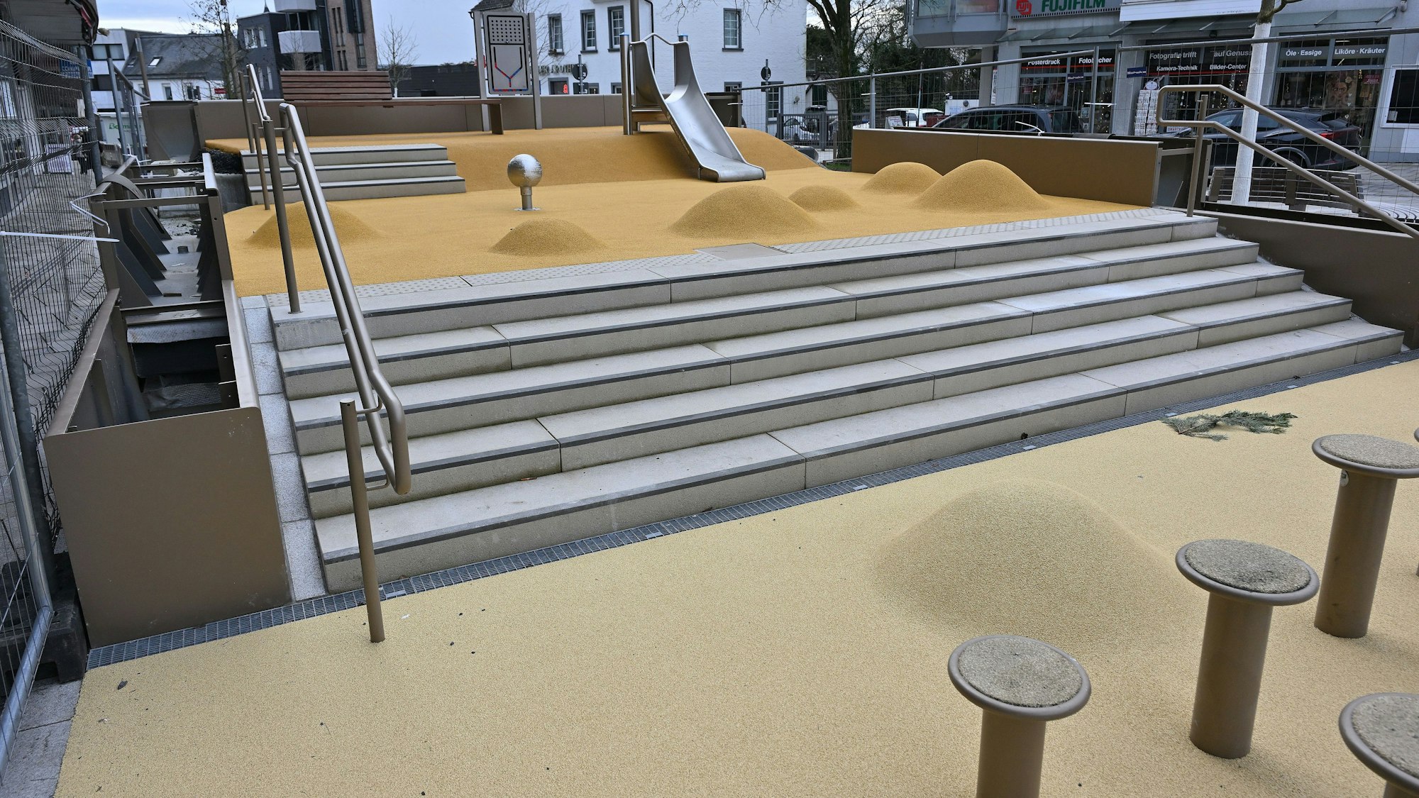 Im Vordergrund sind Sitzpömpel zu sehen, im Hintergrund kleine Hügel sowie eine Rutsche.