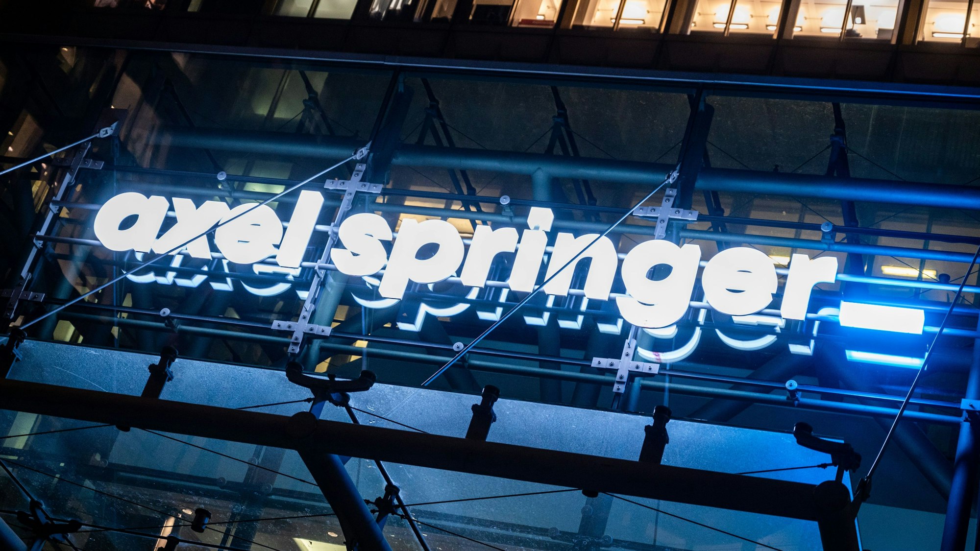 Das Bild zeigt das Logo des Axel Springer-Verlags, das über dem Eingang der Zentrale in Berlin hängt. Foto: Christophe Gateau/dpa