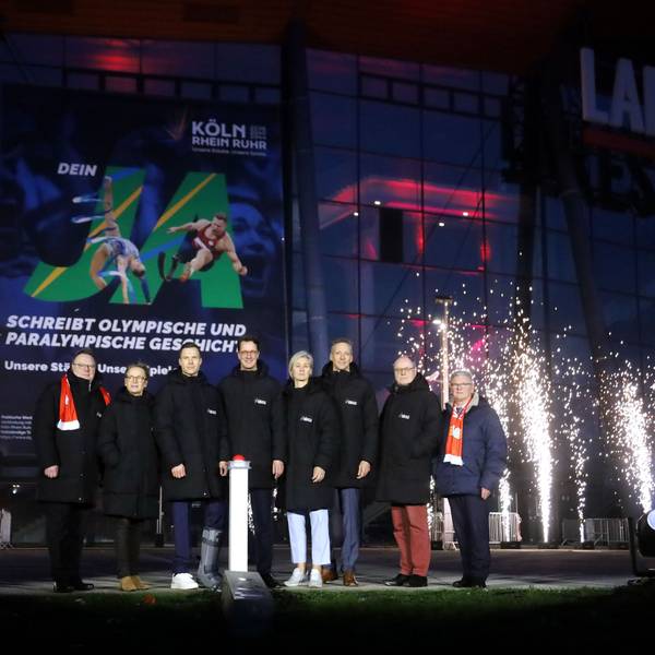 Kölns OB Torsten Burmester (l.) und NRW-Ministerpräsident Hendrik Wüst (4. v. l.) beim „Buzzer-Moment“ für Olympia vor der Lanxess-Arena.