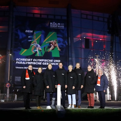 Kölns OB Torsten Burmester (l.) und NRW-Ministerpräsident Hendrik Wüst (4. v. l.) beim „Buzzer-Moment“ für Olympia vor der Lanxess-Arena.