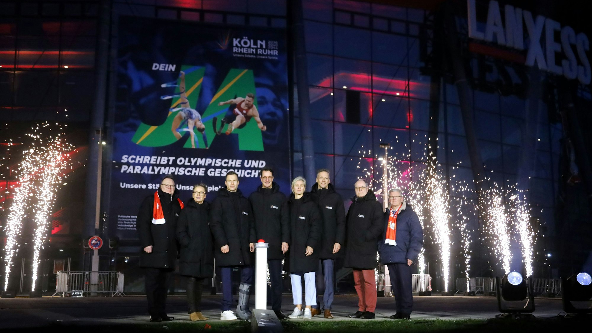 Kölns OB Torsten Burmester (l.) und NRW-Ministerpräsident Hendrik Wüst (4. v. l.) beim „Buzzer-Moment“ für Olympia vor der Lanxess-Arena.