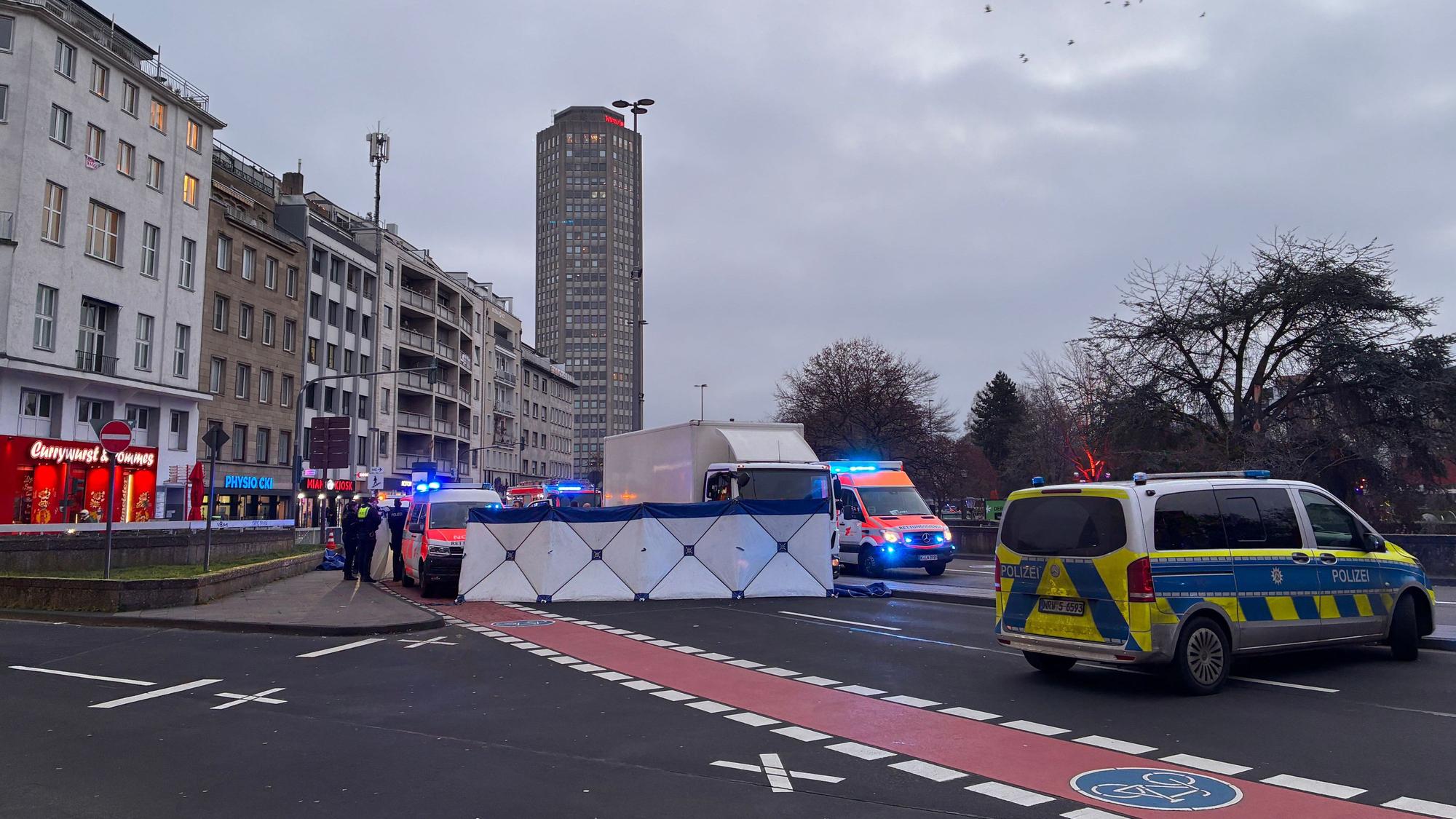 Die Polizei hat auf einer Fahrbahn einen Sichtschutz errichtet, davor stehen ein Lkw sowie Einsatzfahrzeuge von Polizei und Rettungsdienst.